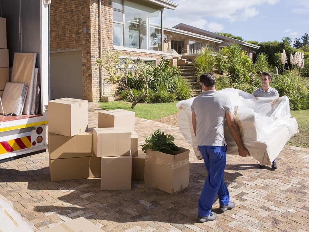 Two movers carrying wrapped couch into moving truck