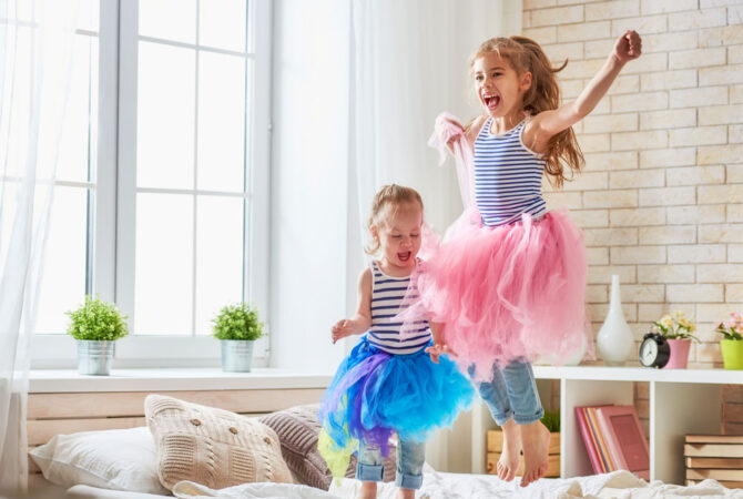 Little girls in shared bedroom jumping on bed