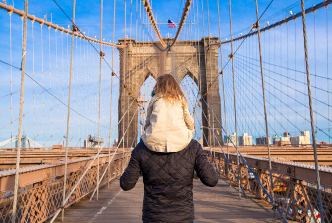 Dad carrying daughter on shoulders on Brooklyn Bridge