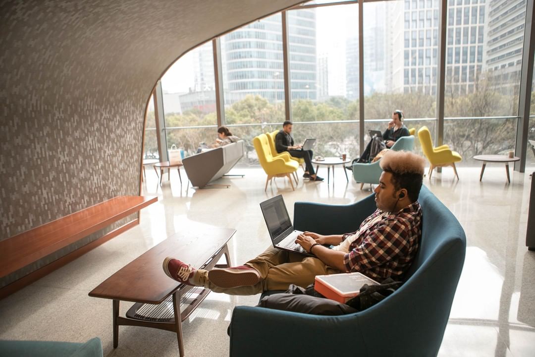 College Student on Computer on Couch in Student Union. Photo by Instagram user @nyuniversity