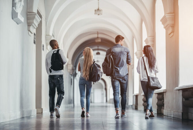 Four college students walking down hallway.