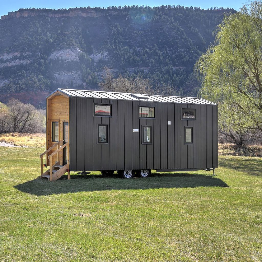 https://www.extraspace.com/blog/wp-content/uploads/2019/11/brown-tiny-home-with-moutains-and-gress--1024x1024.jpeg