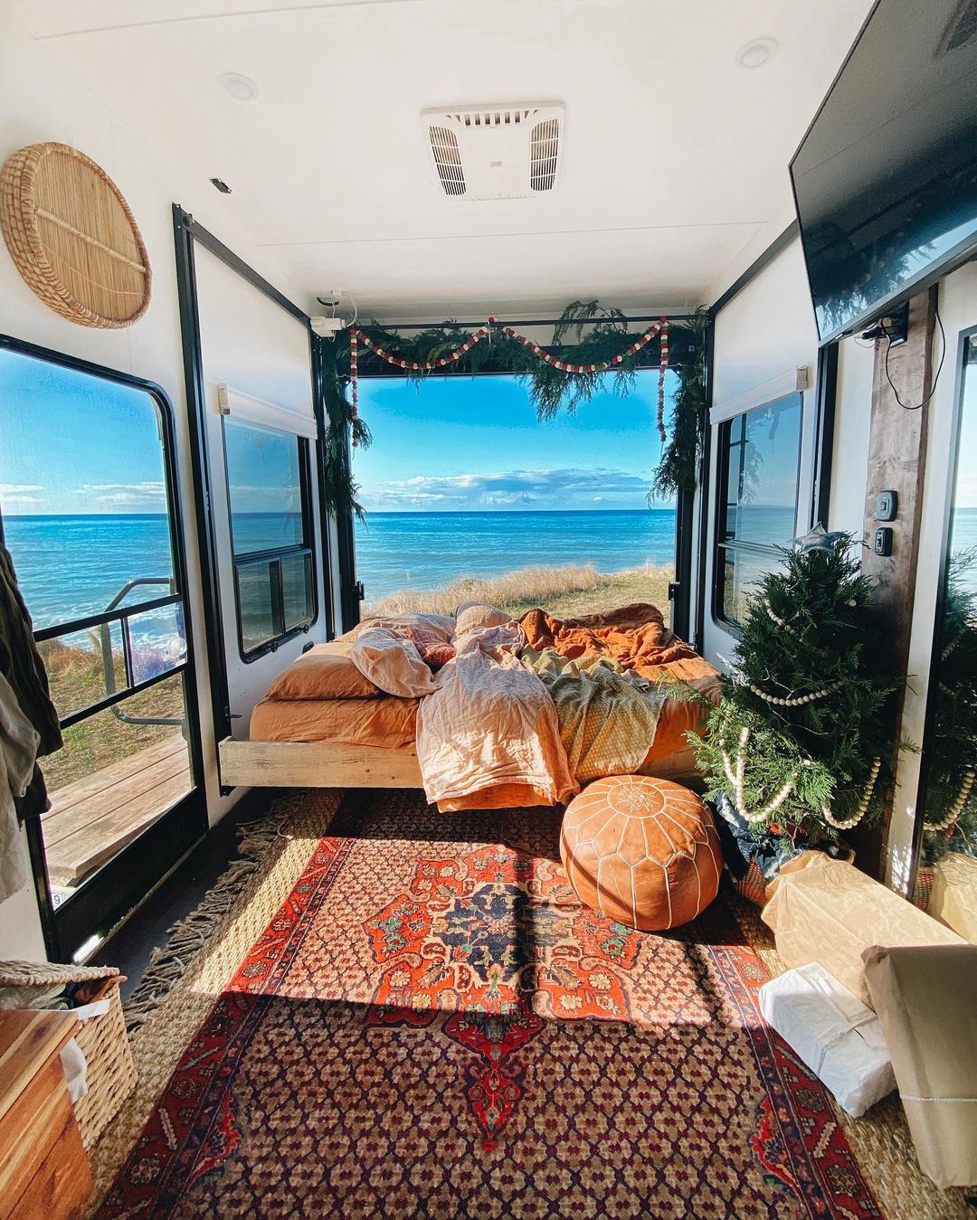 View of main bedroom of RV, with large glass windows and doors to reveal ocean views. Photo by Instagram user @theasphaltgypsy.