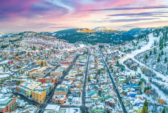 Arial shot of Park City, Utah, in the winter with a colorful landscape, painted houses, and a beautiful sunset.