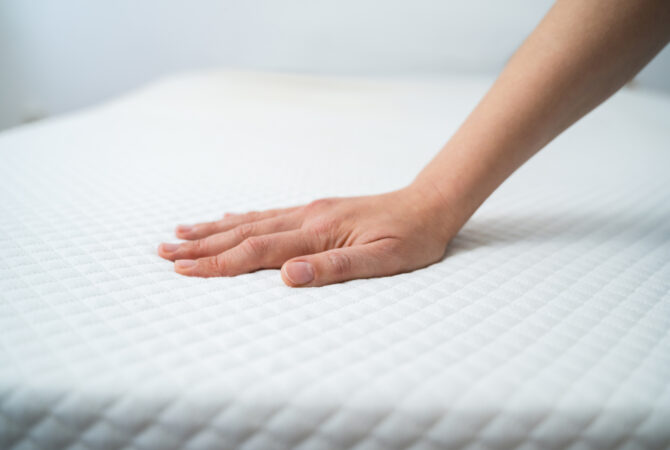 Stock photo of a hand testing an orthopedic white mattress