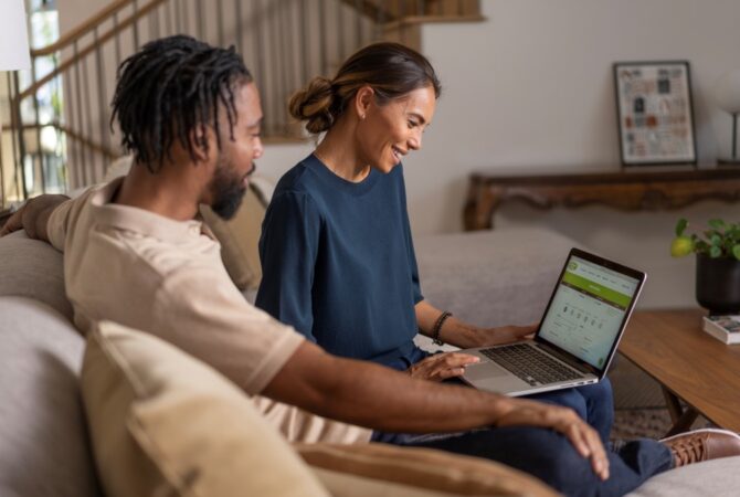 Couple in living room looking at Extra Space Storage website on laptop