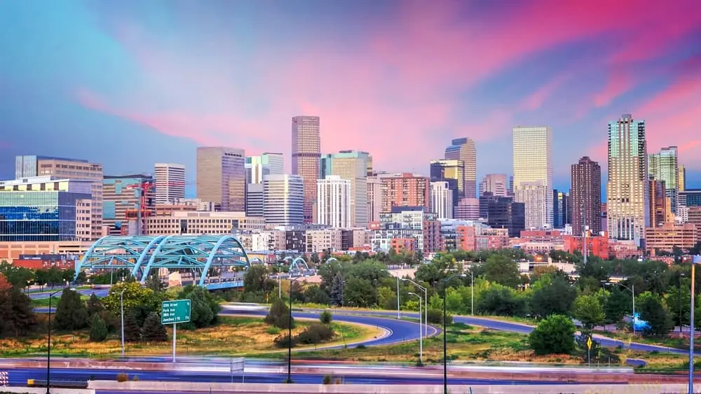Vibrant Denver skyline photo at twilight with blue and pink skies.