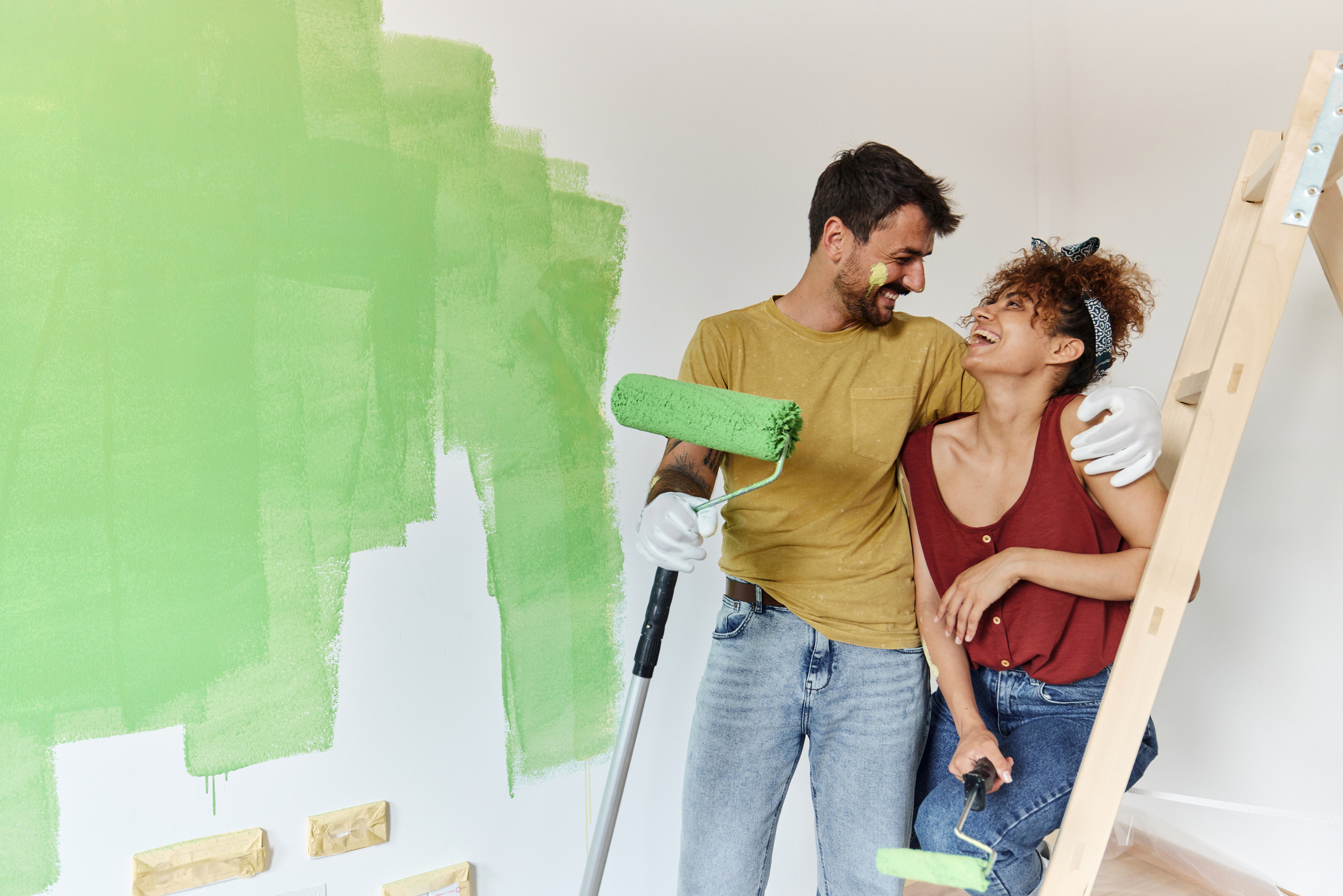 moving into a new house - Young happy couple communicating on a break from painting their walls